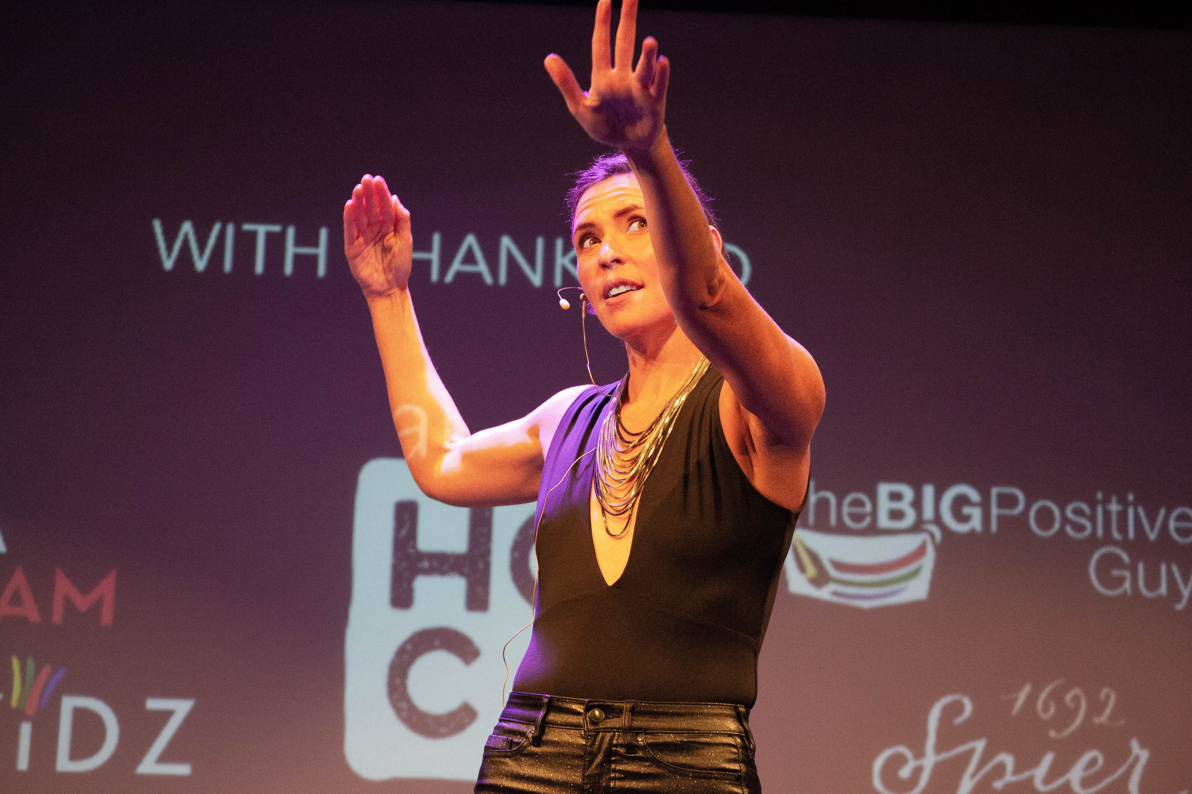 Resilience keynote speaker Carina Bruwer on stage with arms raised